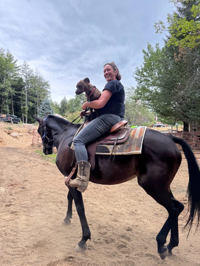 Wendy on horseback with a dog in the saddle